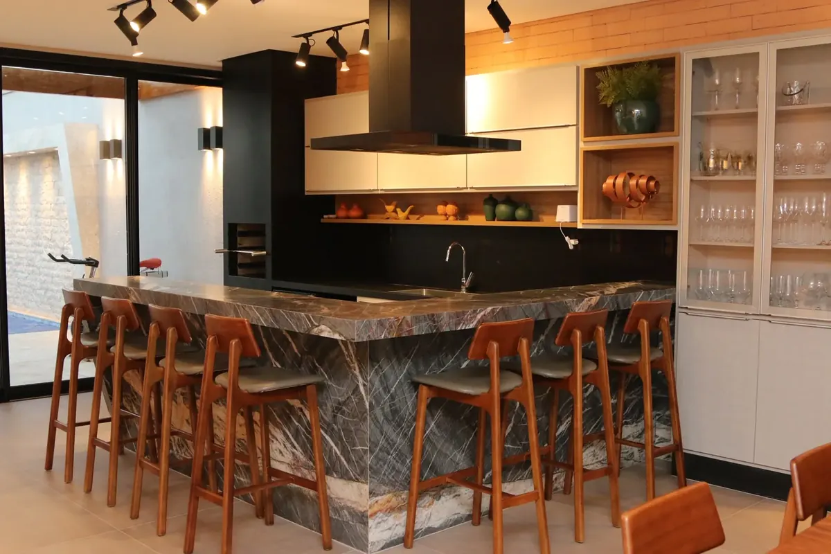 Bar com bancada em pedra e banquetas de madeira