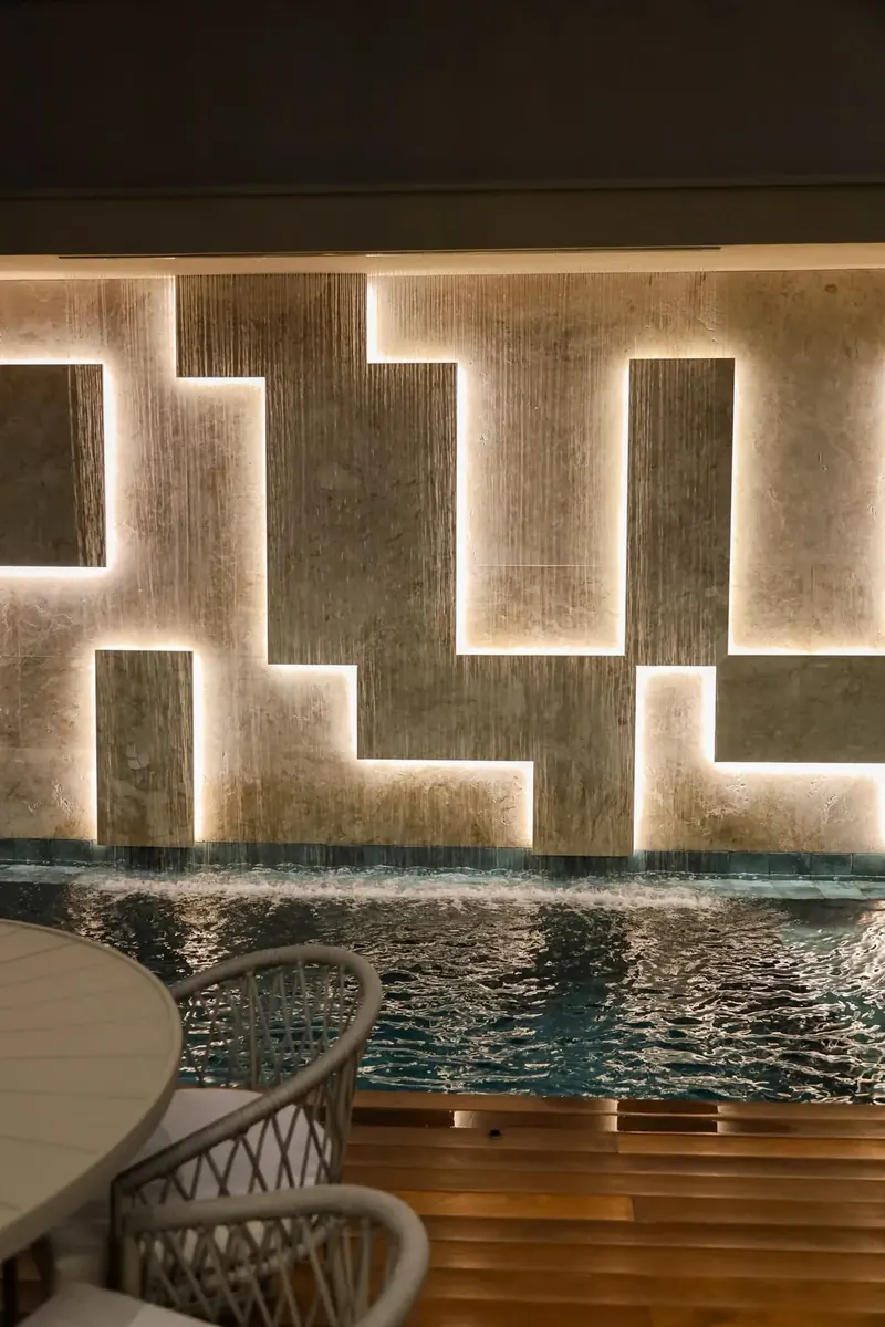 Parede de pedra retroiluminada à beira da piscina