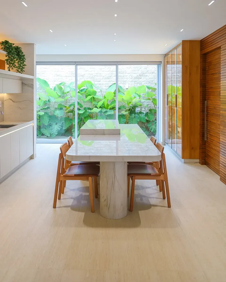 Sala de jantar com mesa em mármore e vista para o jardim